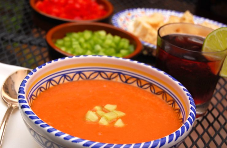 gazpacho dentro ad una ciotola con accanto un bicchiere di sangria