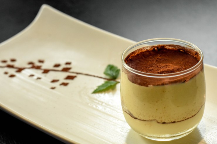 tiramisù in un bicchiere sopra ad un piatto 